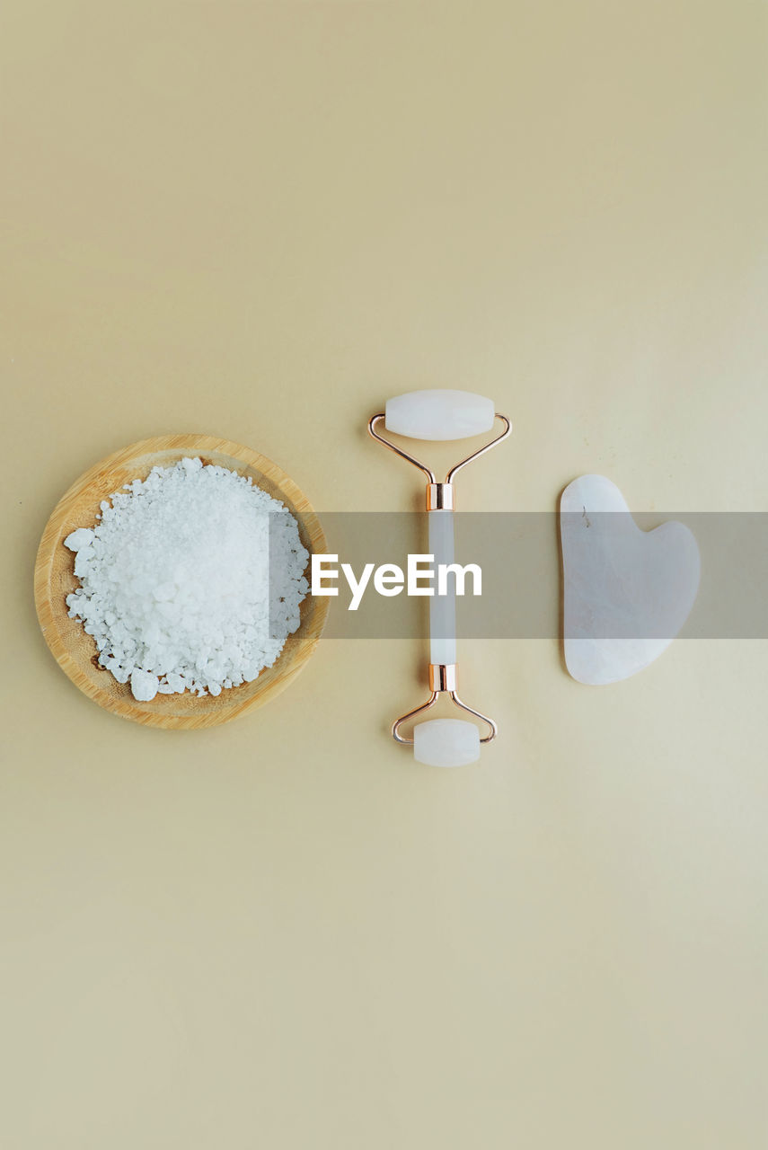 Skin scrub on  wooden plate, a roller for the face and a  scraper. cosmetic care at home layout. 