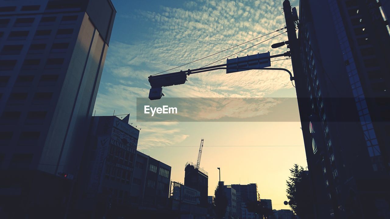 Low angle view of buildings against cloudy sky during sunset