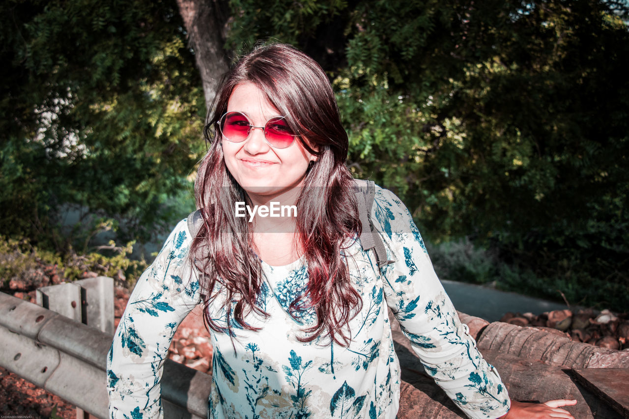 PORTRAIT OF YOUNG WOMAN WEARING SUNGLASSES