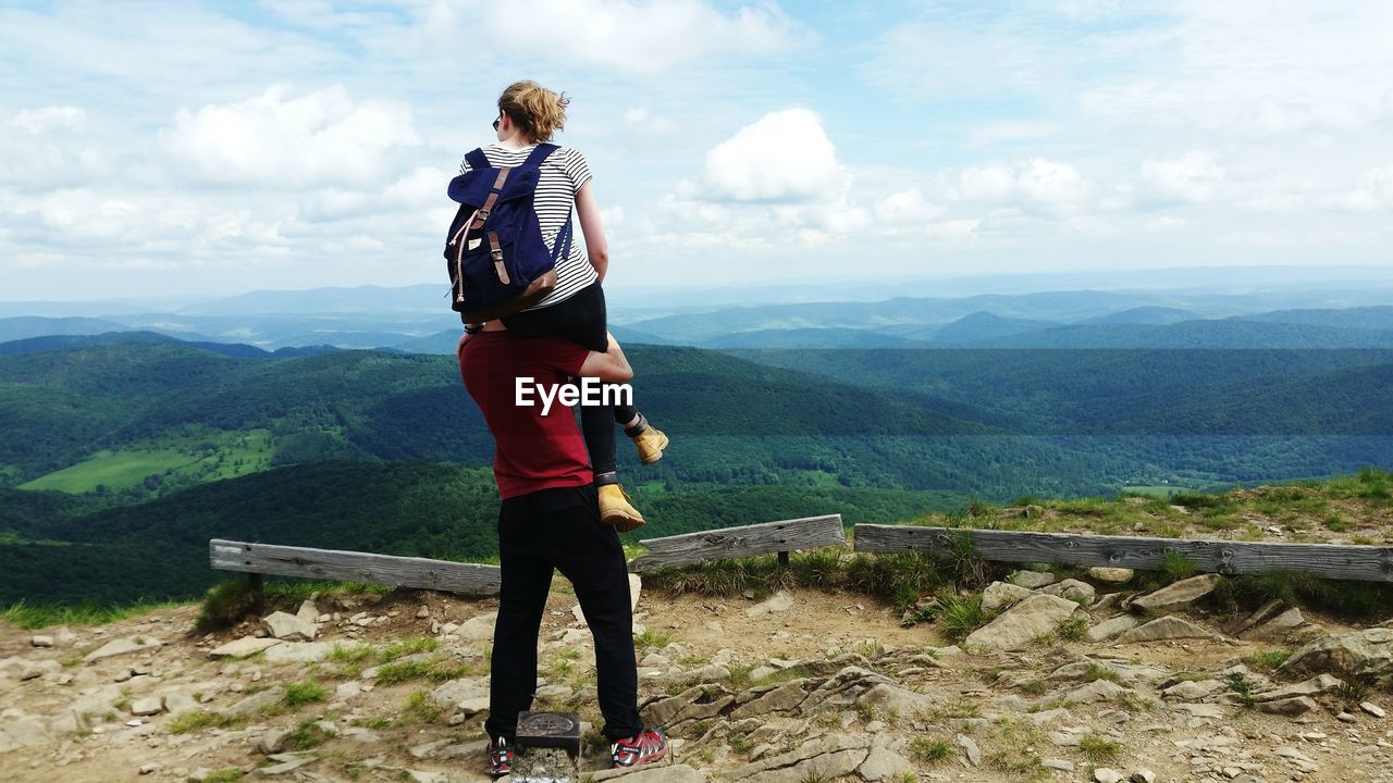 Rear view of man carrying woman enjoying the mountain view