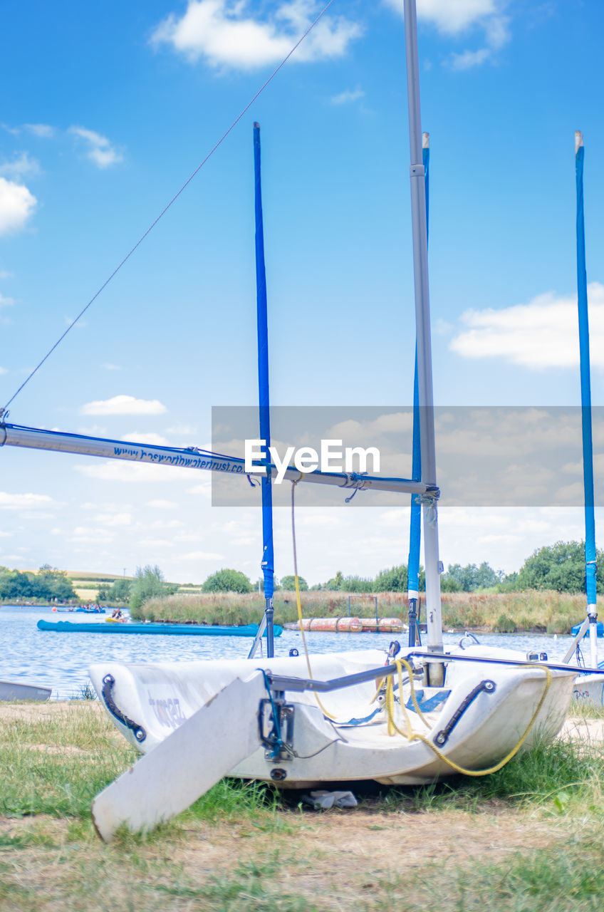 BOAT MOORED ON FIELD AGAINST SKY