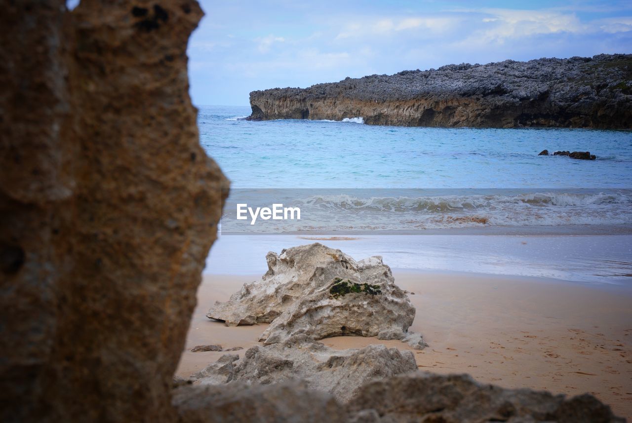 Rock formation on beach against sky