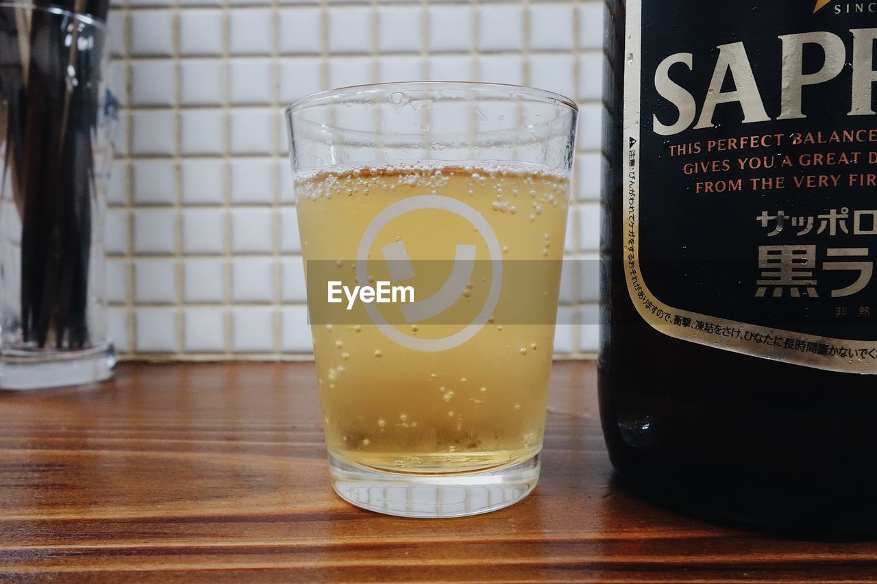 CLOSE-UP OF BEER GLASS ON TABLE WITH TEXT