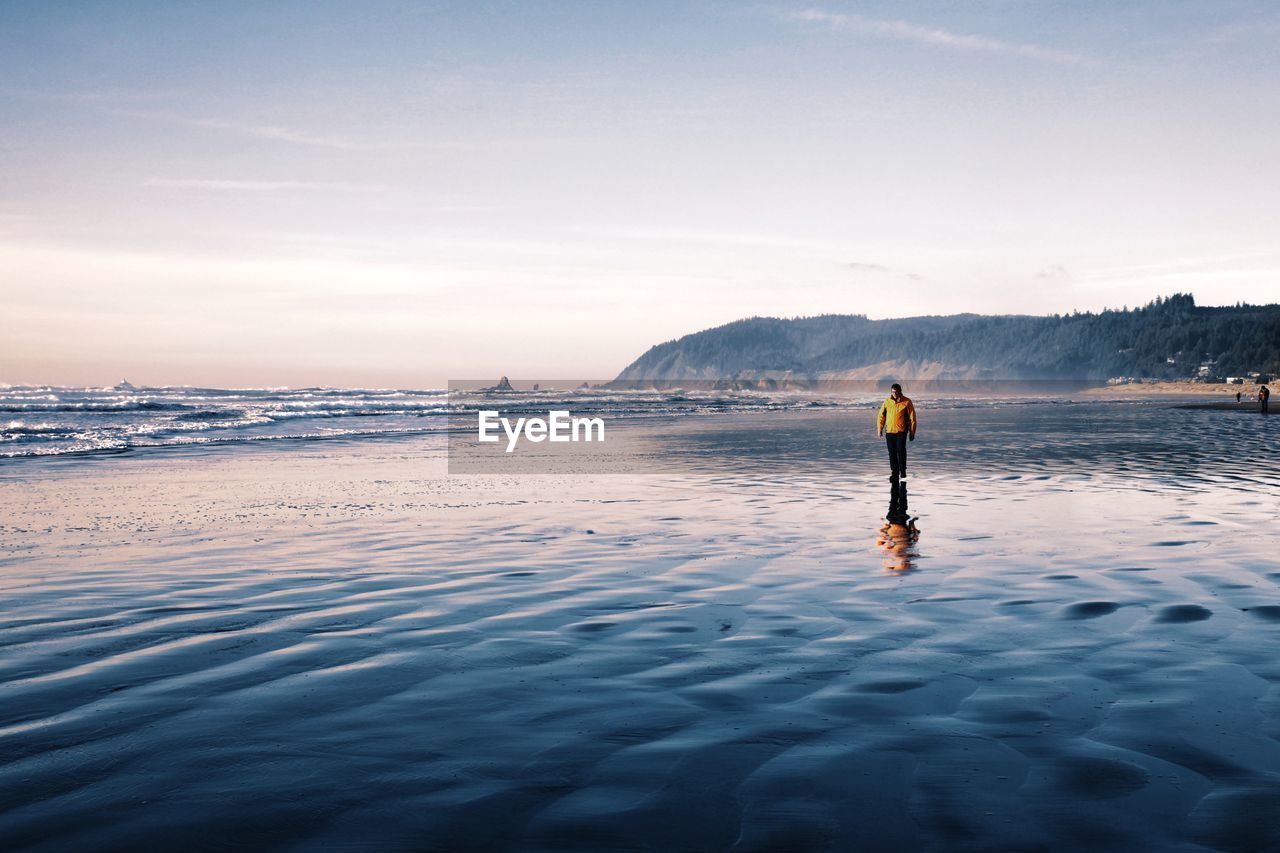 Man standing at beach against sky