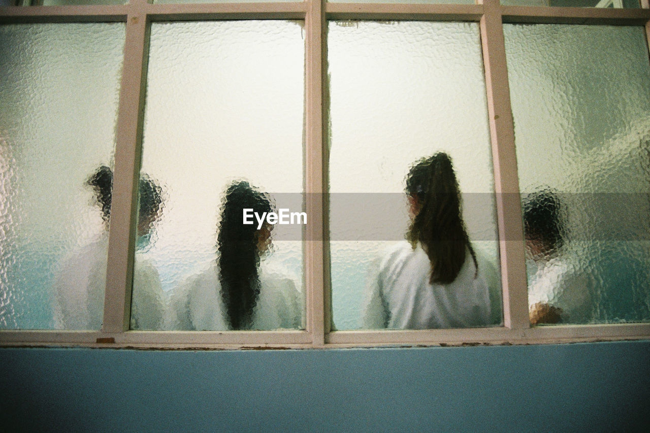 WOMAN LOOKING THROUGH WINDOW IN GLASS