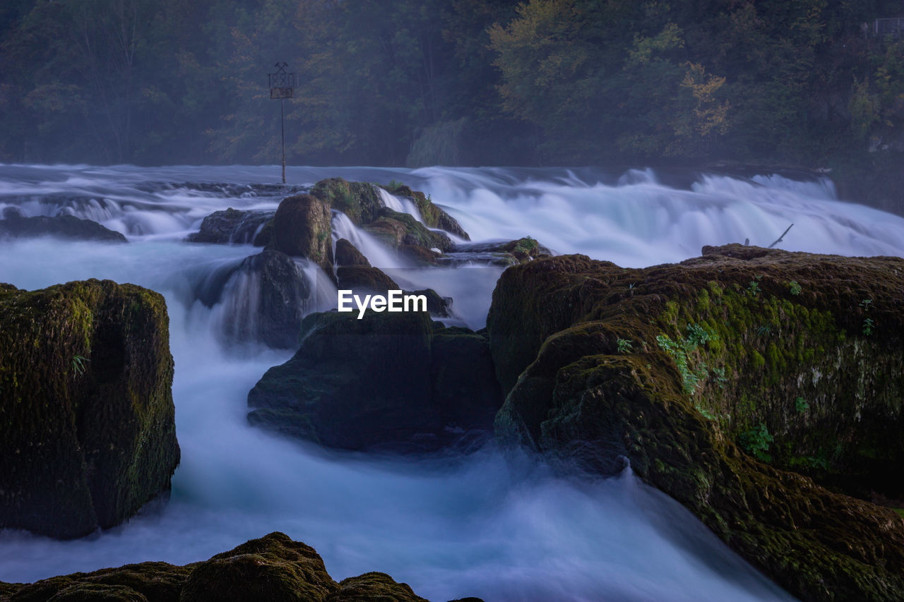 SCENIC VIEW OF WATERFALL AGAINST ROCKS