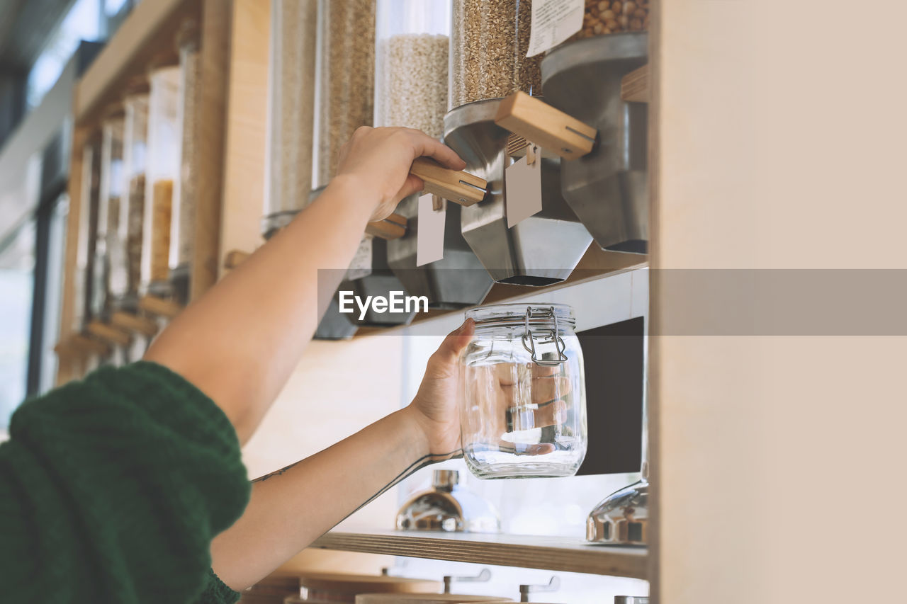 Customer filling lentils in glass jar at zero waste shop