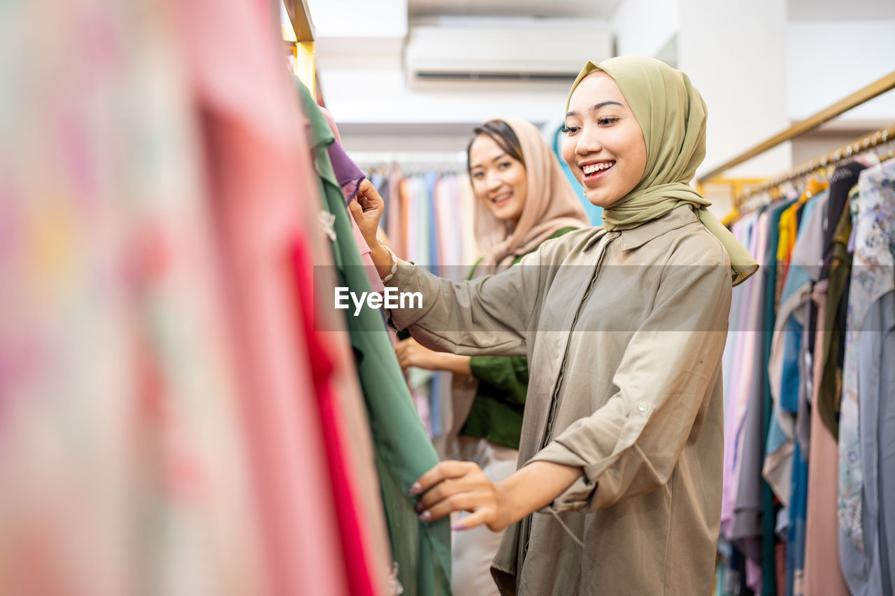 Smiling woman wearing hijab shopping in store
