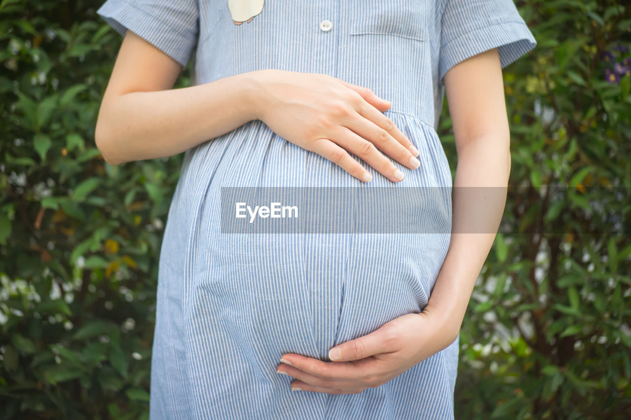 Midsection of pregnant woman standing at park