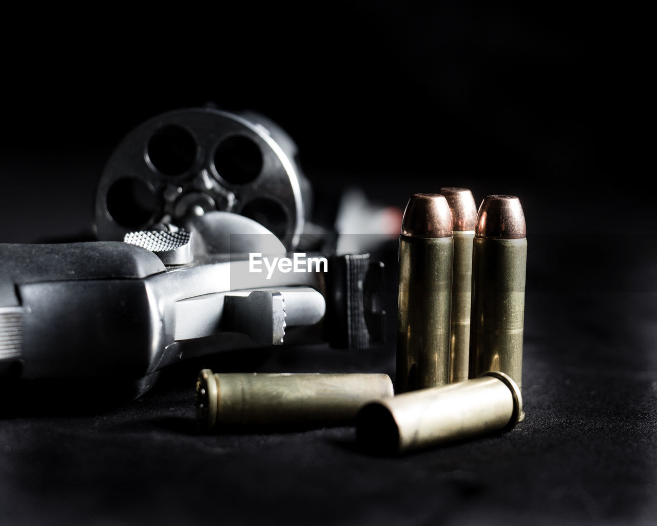 Close-up of gun and bullets against black background