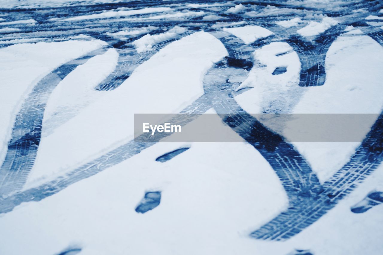 HIGH ANGLE VIEW OF TIRE TRACKS ON SNOWY DAY