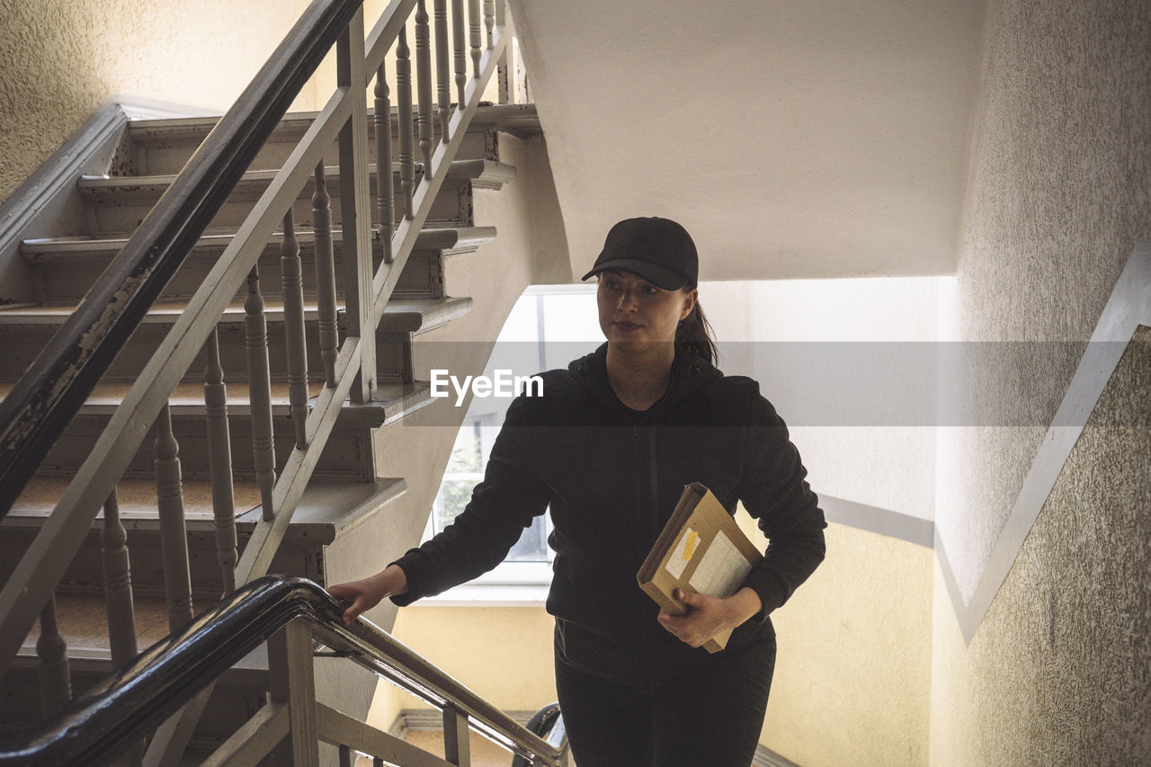 Delivery woman with package climbing staircase