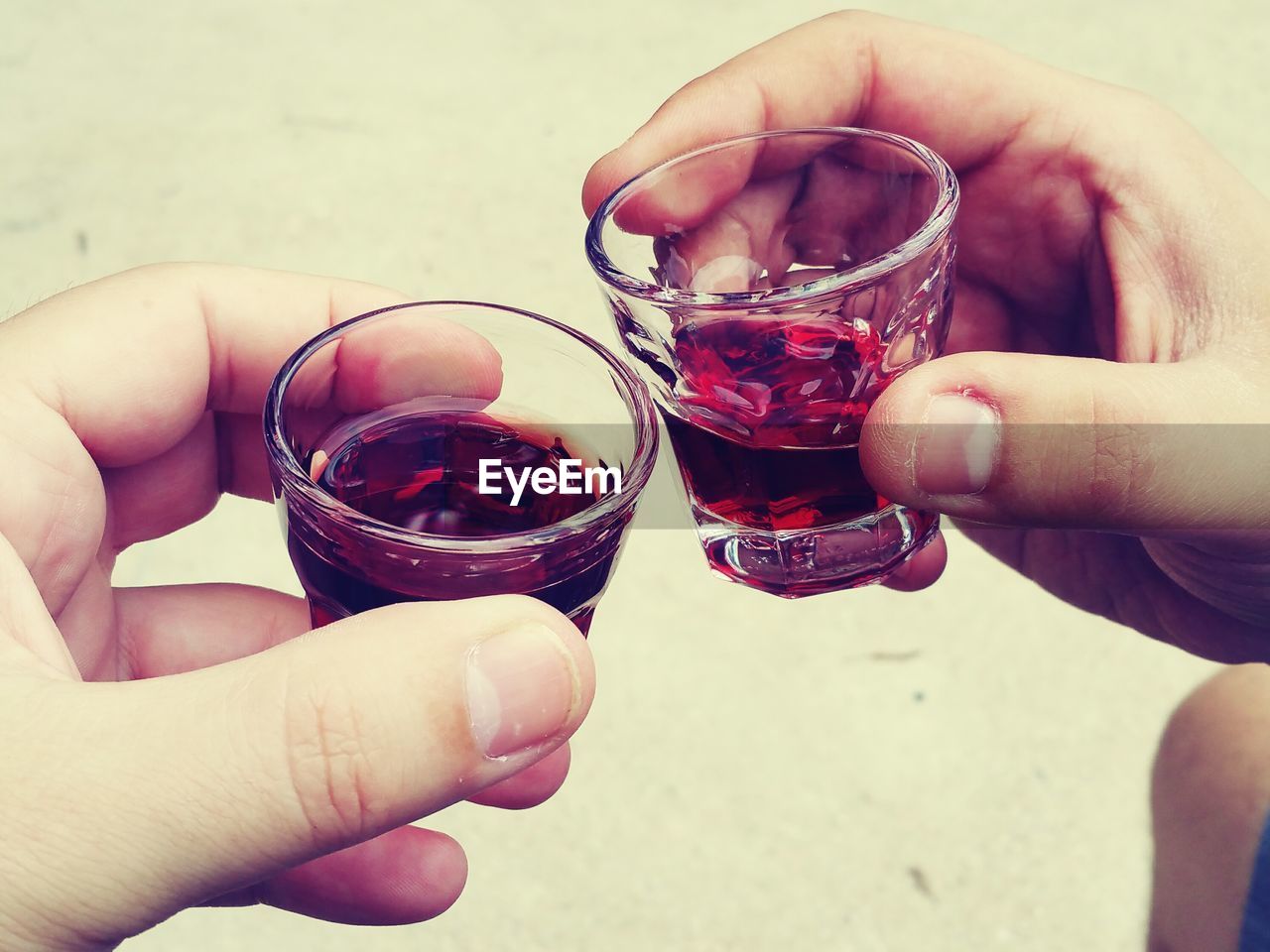Close-up of cropped hands holding glasses of red wine