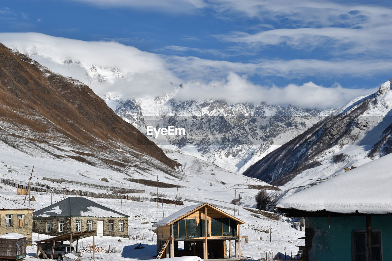 HOUSES ON SNOWCAPPED MOUNTAIN AGAINST SKY