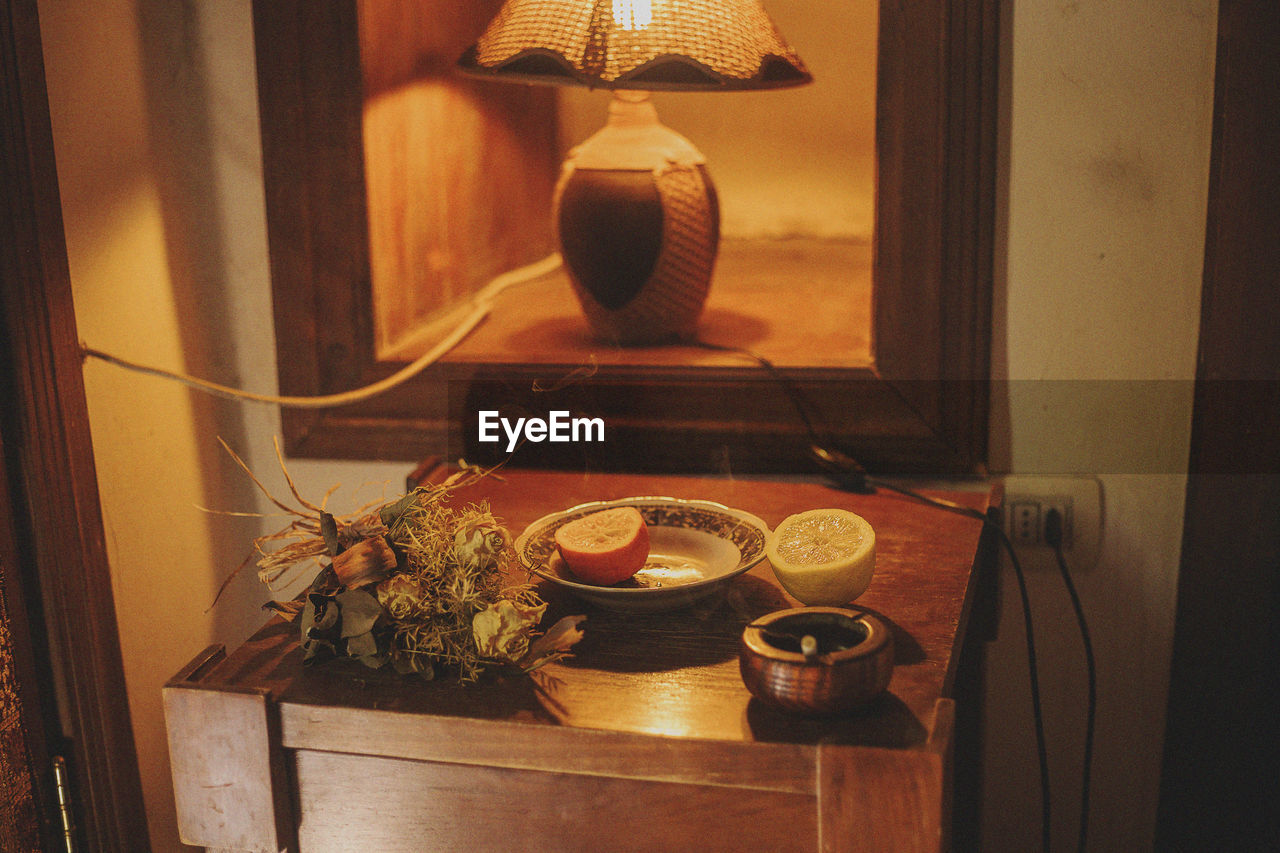 High angle view of citrus fruit on table by illuminated lamp at home