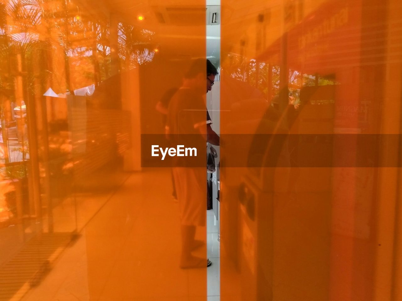 Man standing at home seen through orange curtain