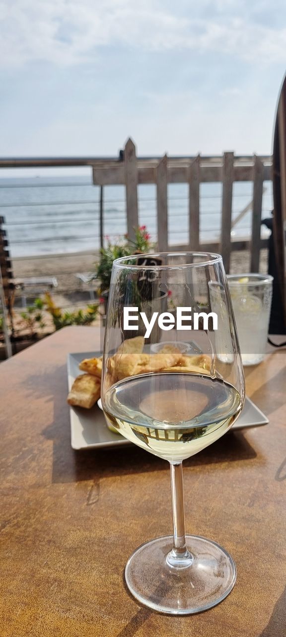 WINE GLASS ON TABLE AGAINST SEA