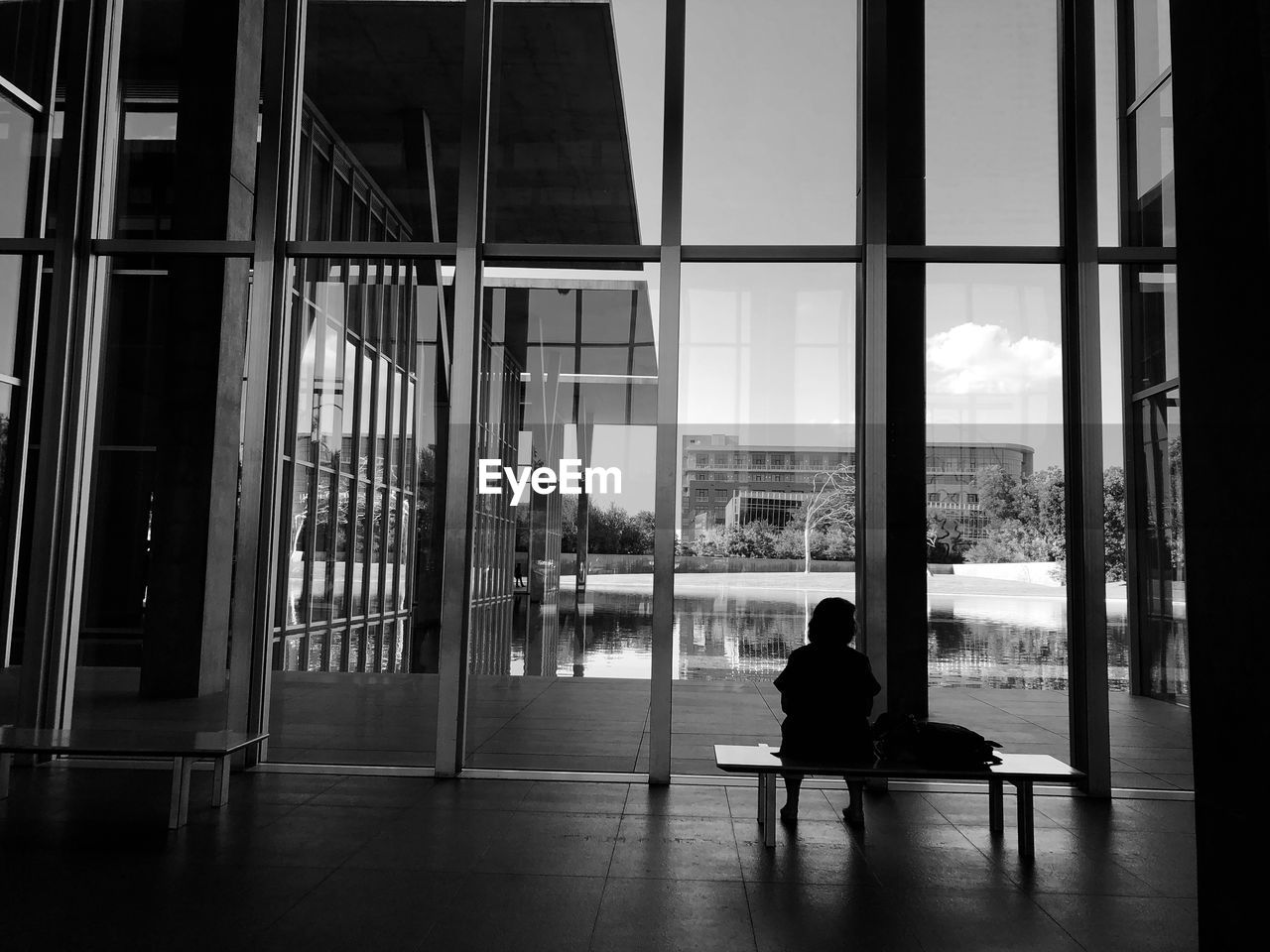 REAR VIEW OF MAN SITTING ON SEAT IN BUILDING