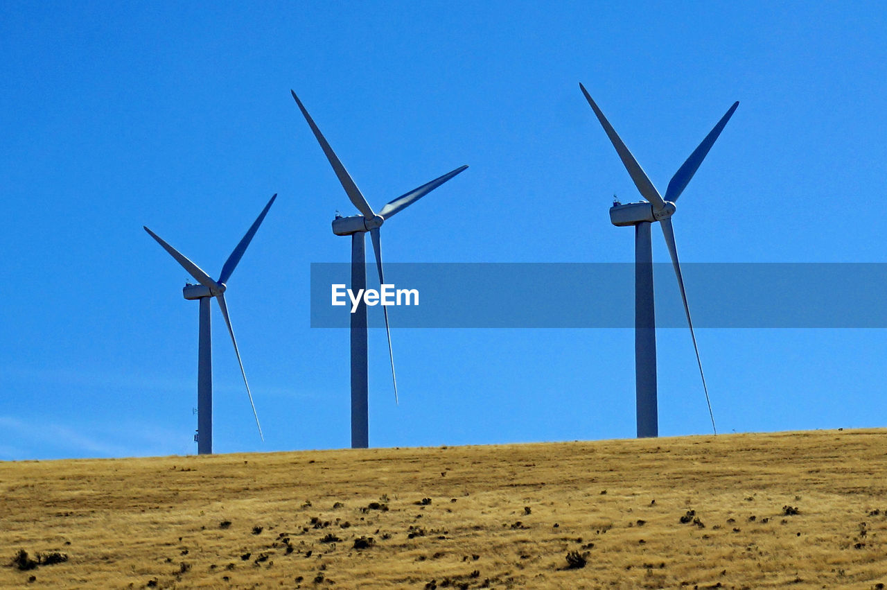 WINDMILL ON FIELD AGAINST CLEAR BLUE SKY