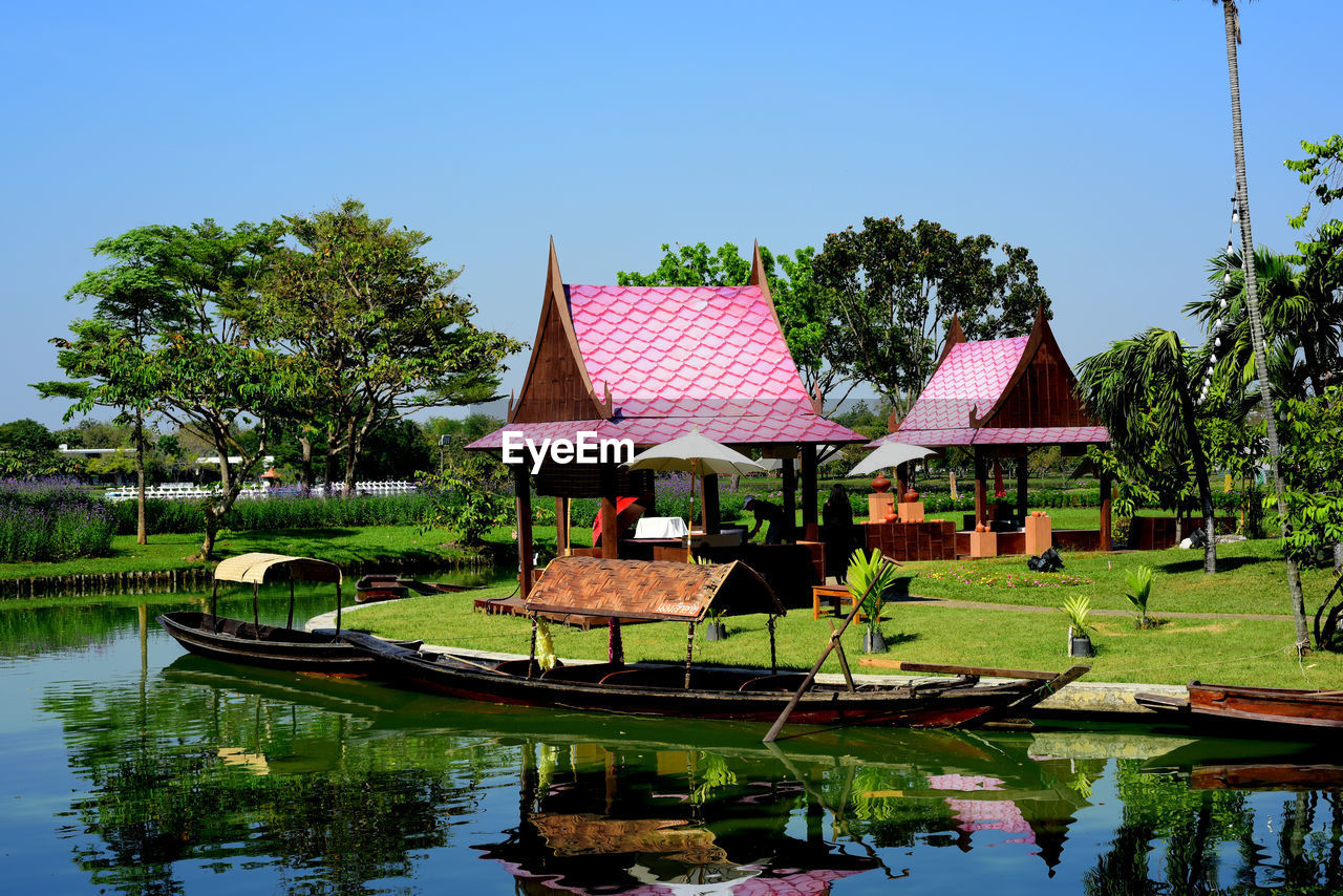 HOUSES BY LAKE AND TREES AGAINST SKY