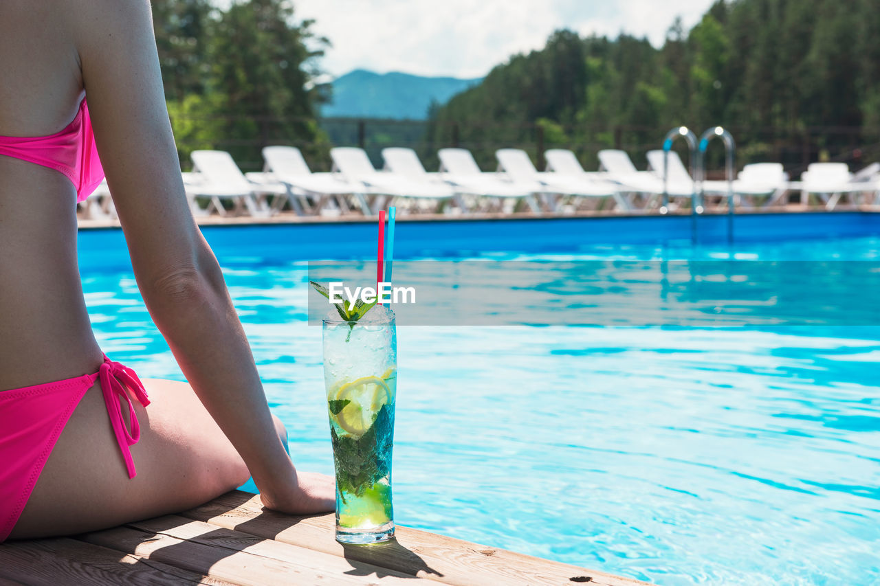 midsection of woman swimming in pool