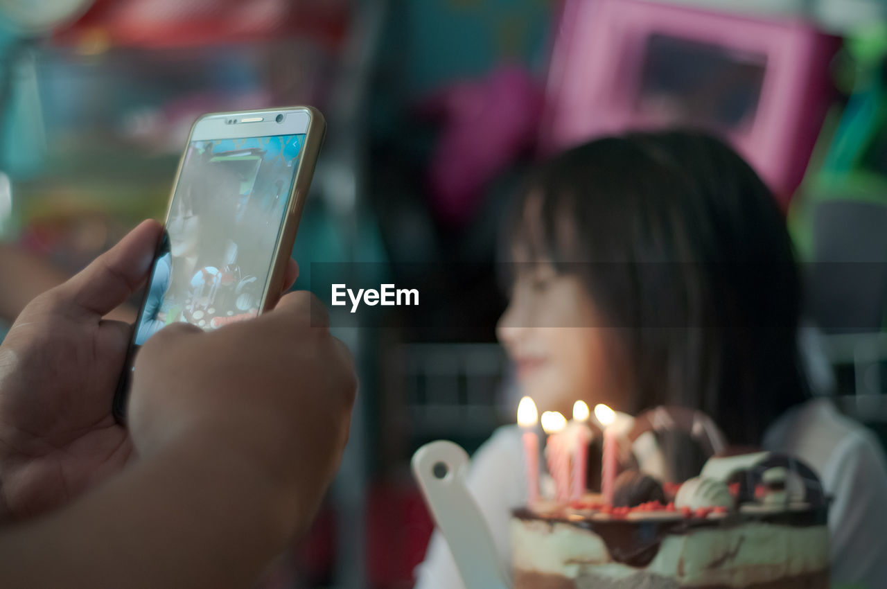 Close-up of cute girl sitting by cake at home