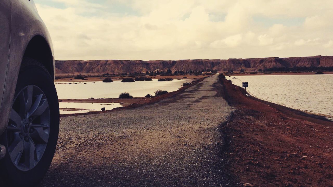 Cropped image of car on road amidst lake