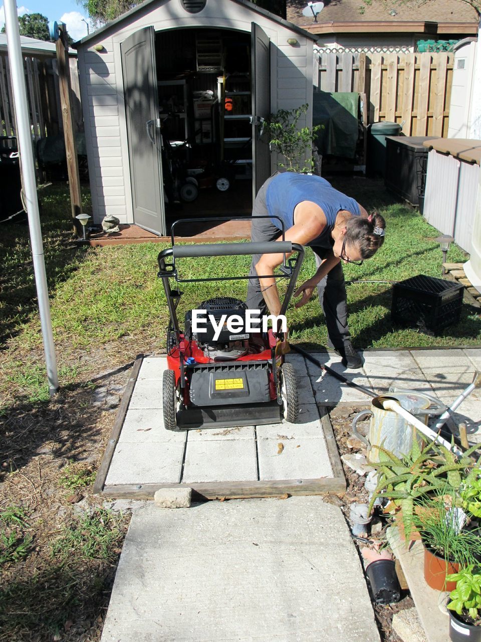 Woman working by lawn mover in yard