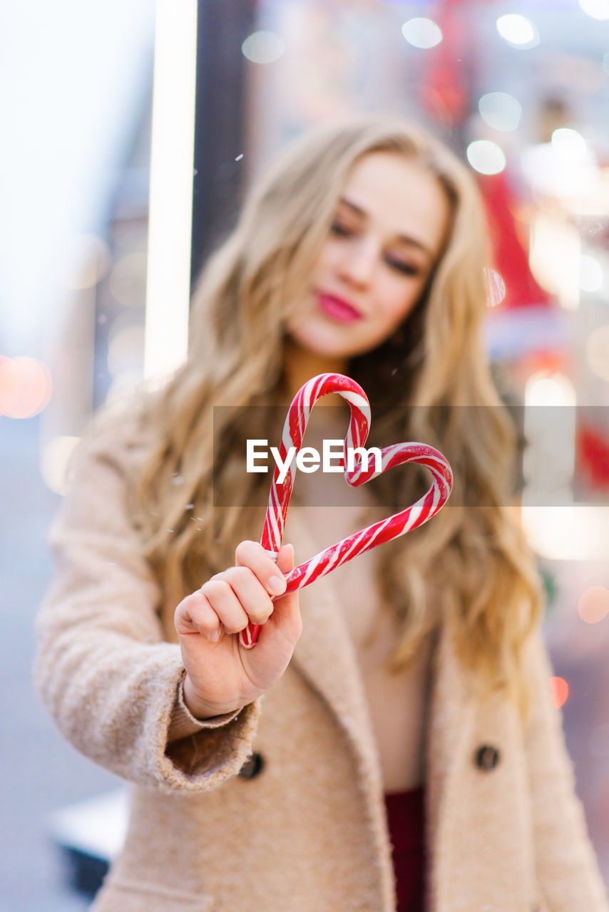 A heart made of two candy canes in the hands of a girl. the concept of the valentine's day holiday