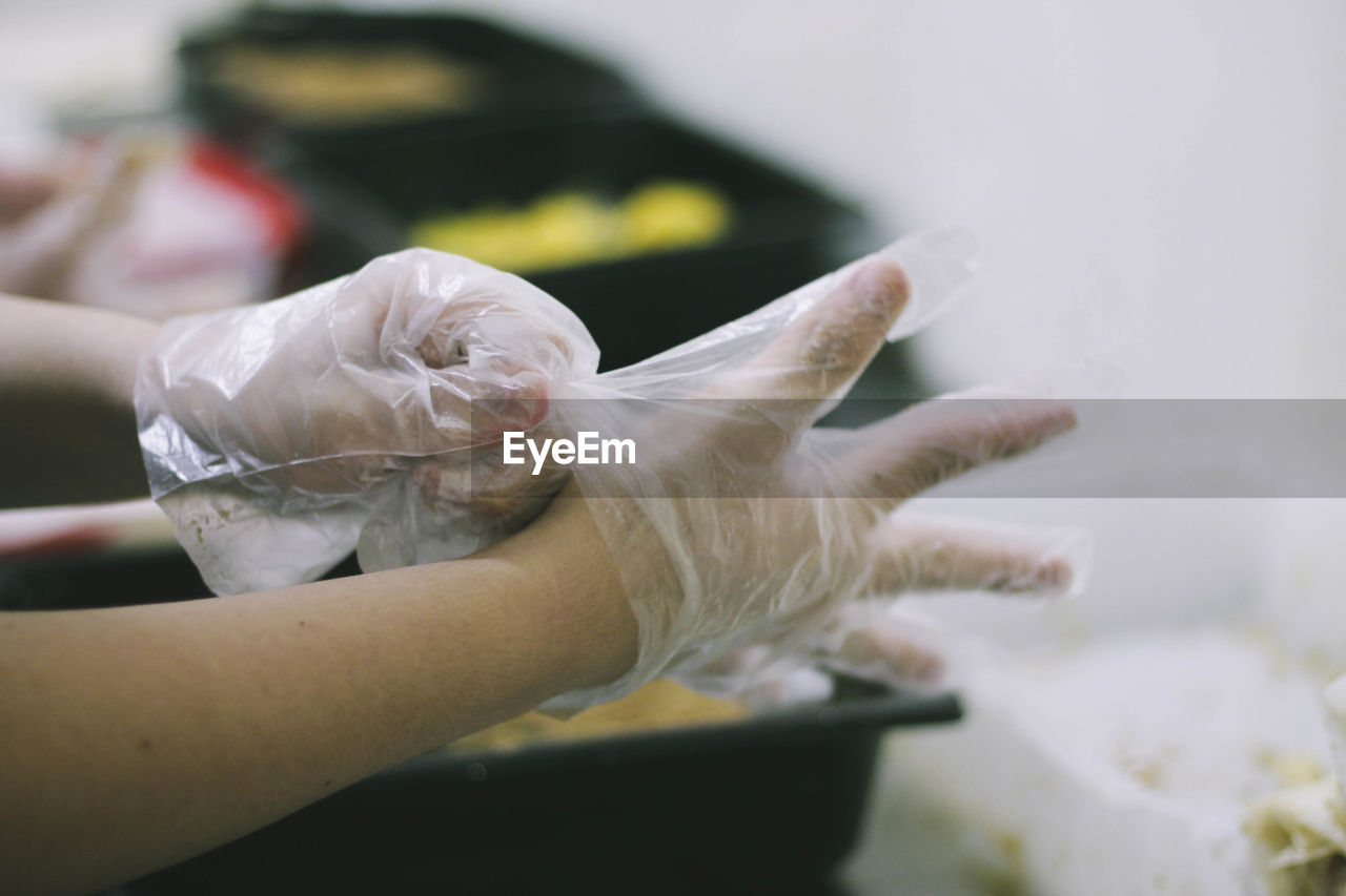 Close-up of cropped hands wearing plastic gloves
