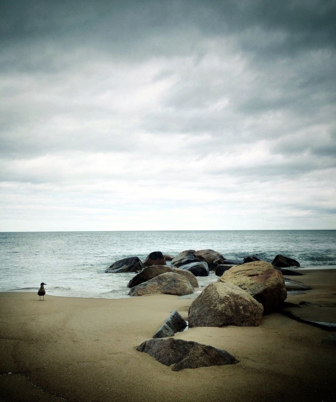 View of calm beach against cloudy sky