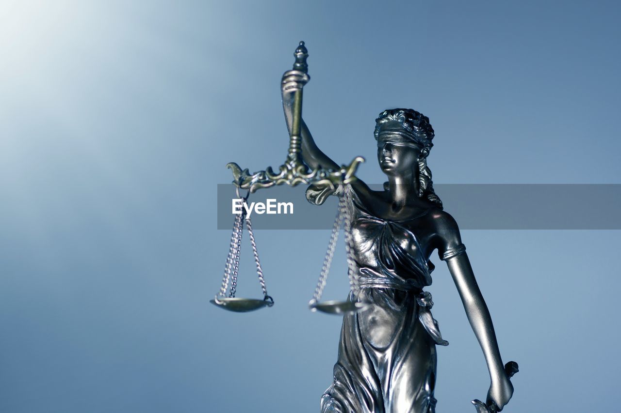 Low angle view of lady justice against clear blue sky