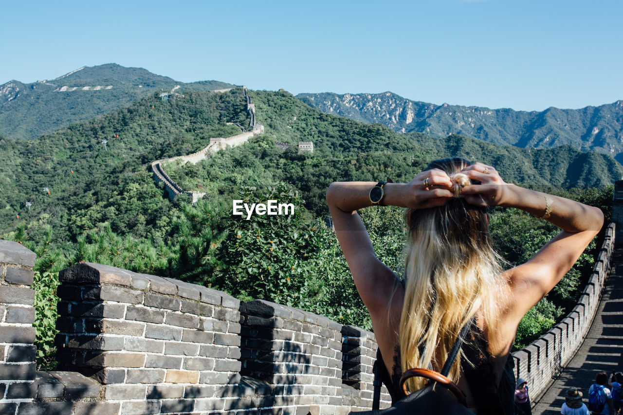 Rear view of woman tying hair while standing at great wall of china