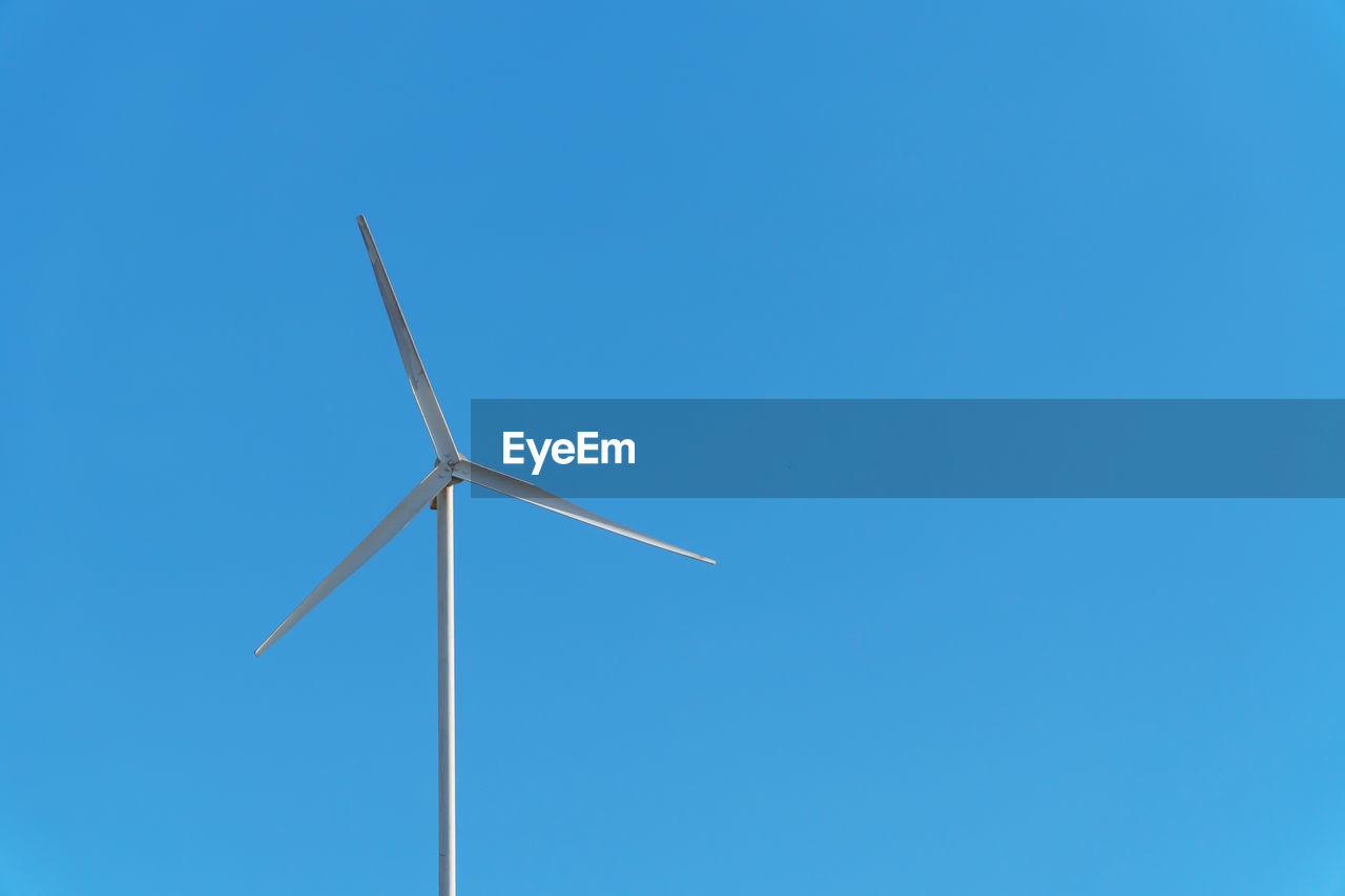 LOW ANGLE VIEW OF WINDMILL AGAINST CLEAR BLUE SKY