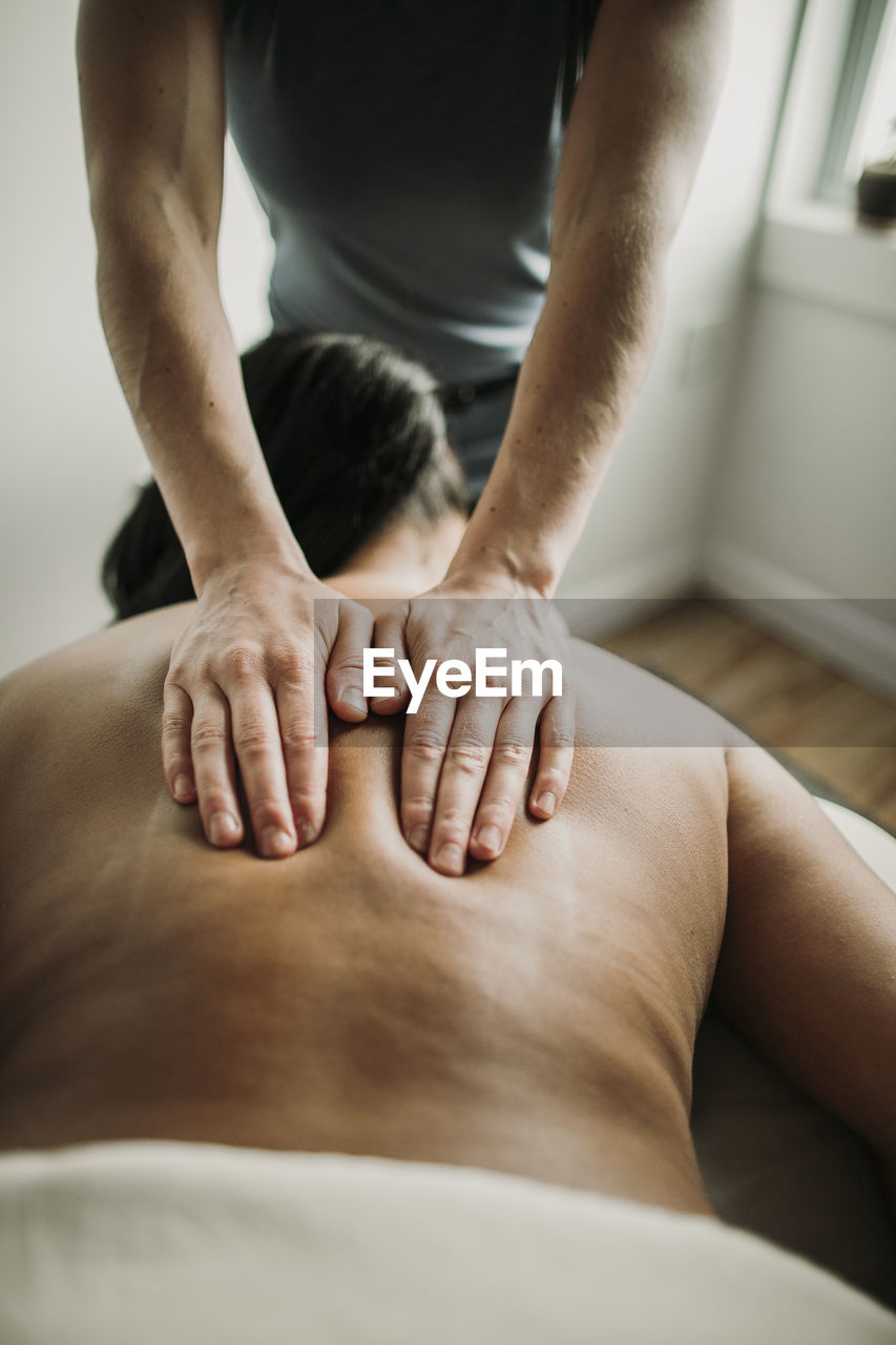 Detail of a massage therapists hands on the back of her patient.