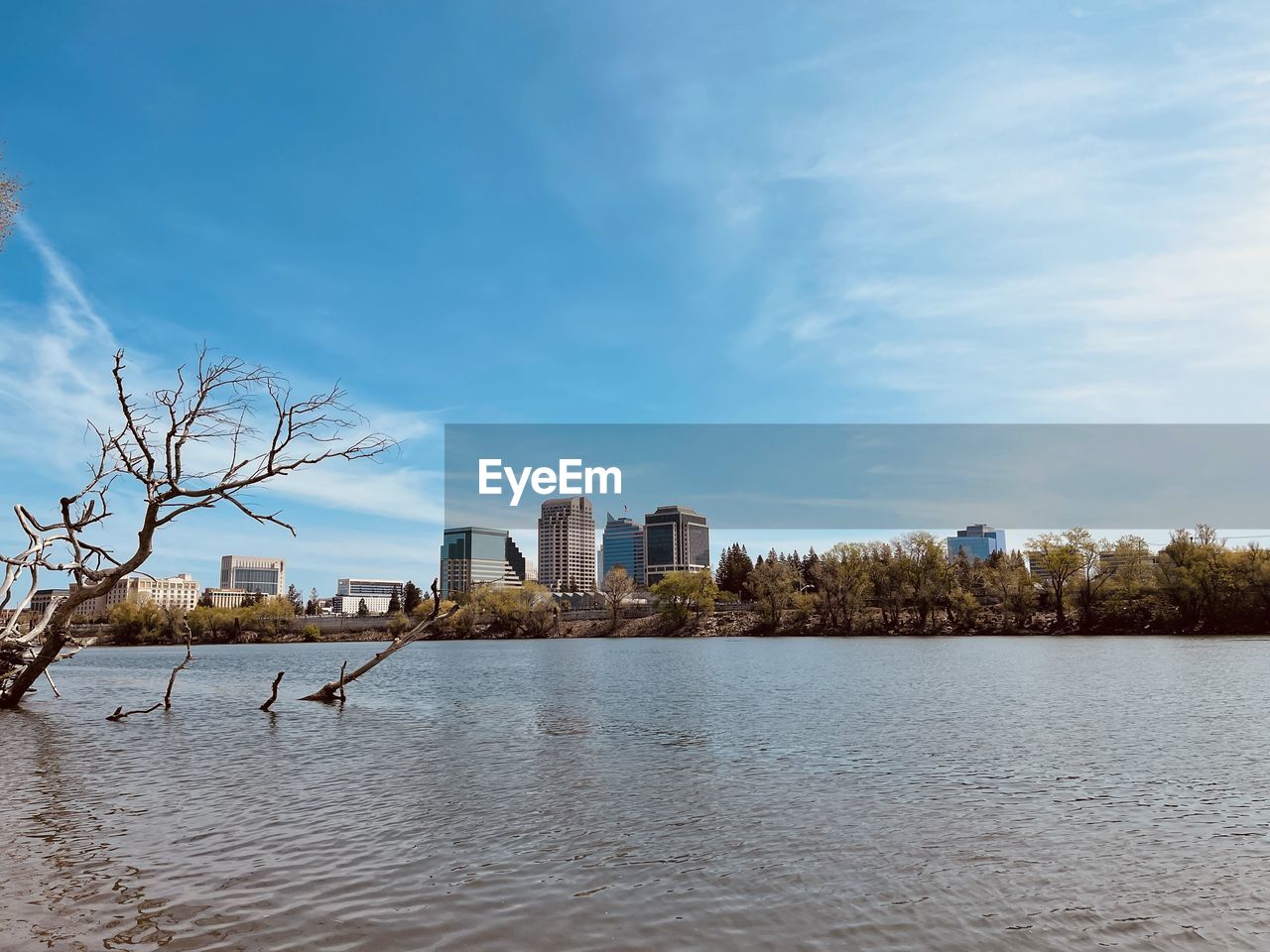 Buildings by river against sky in city