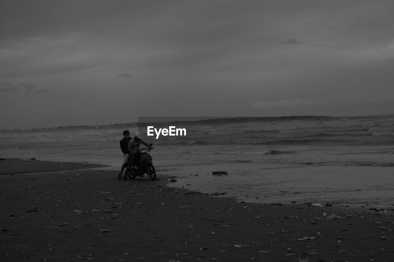 MAN ON BEACH AGAINST SKY