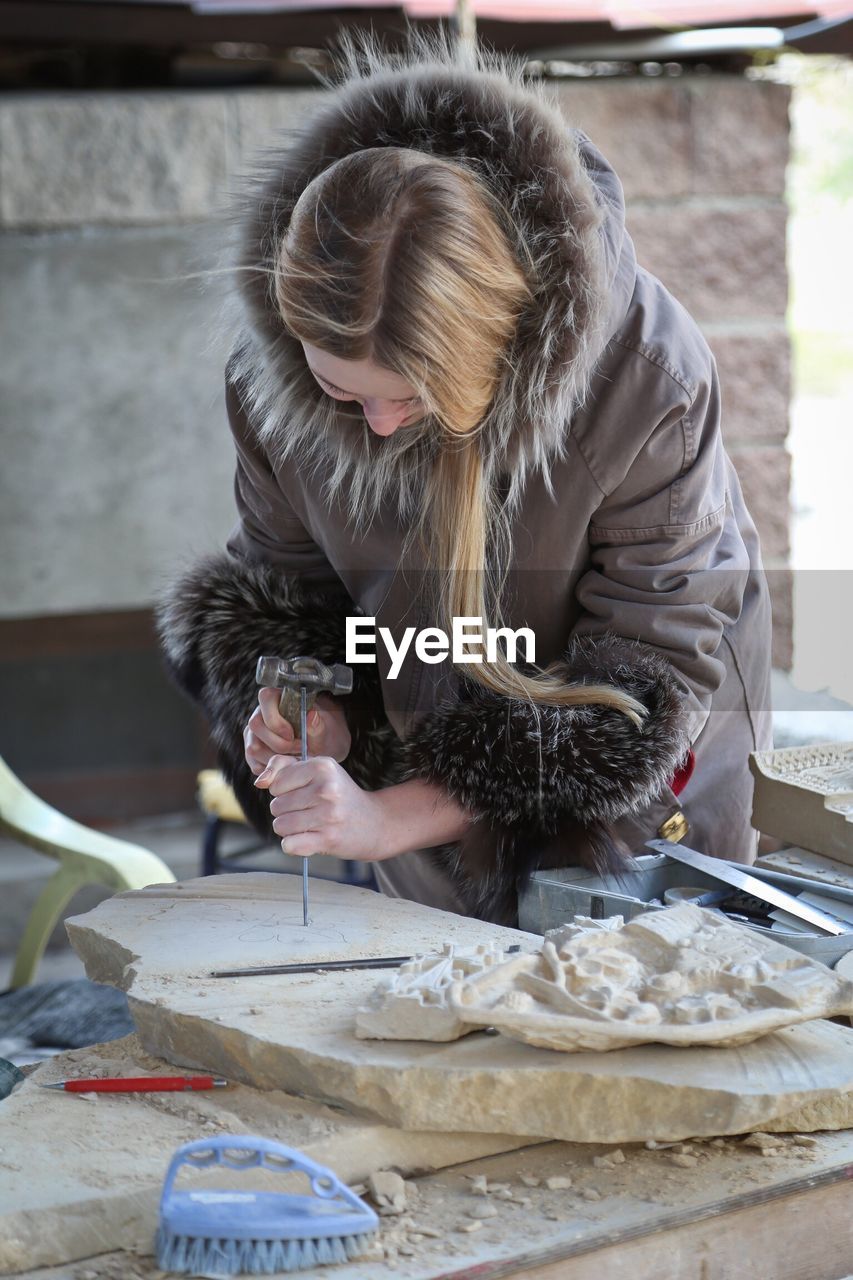 Young woman working on stone