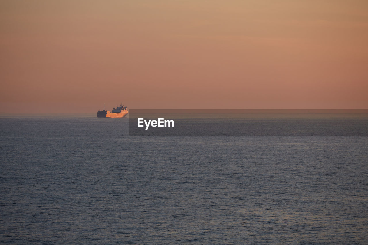 Commercial ship crossing the sea at sunset.