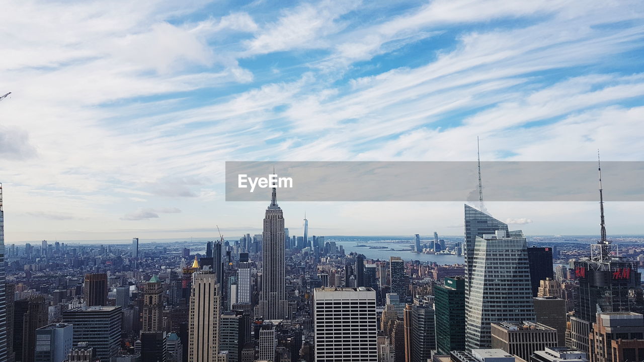 Modern buildings in city against cloudy sky