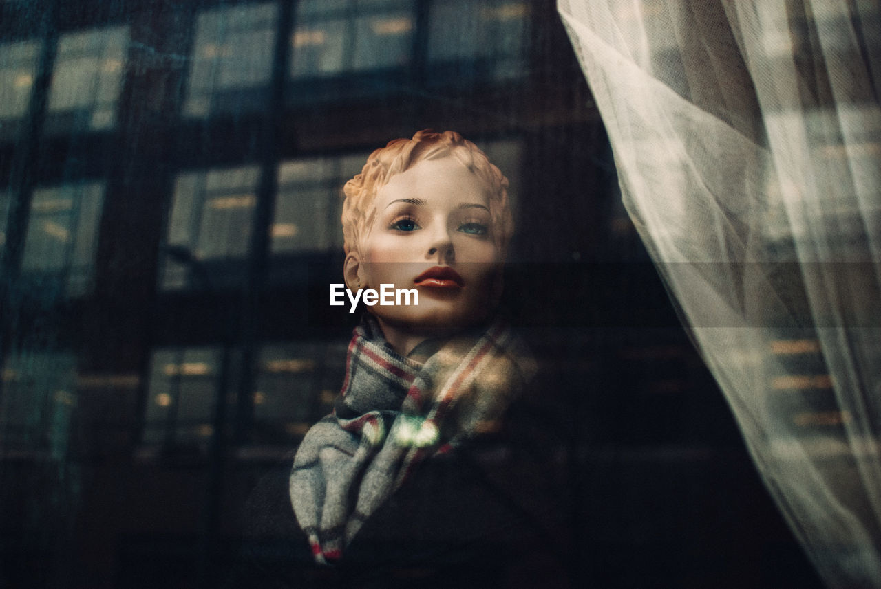 Mannequin in clothing store seen through glass window