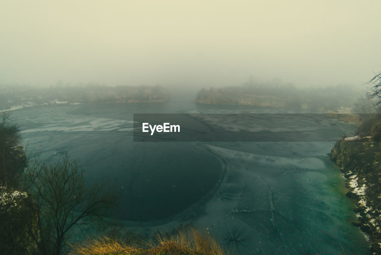 Scenic view of frozen landscape against sky during foggy weather