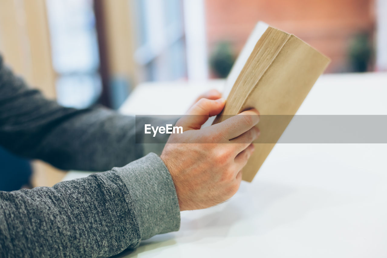 CLOSE-UP OF MAN HAND HOLDING BOOK