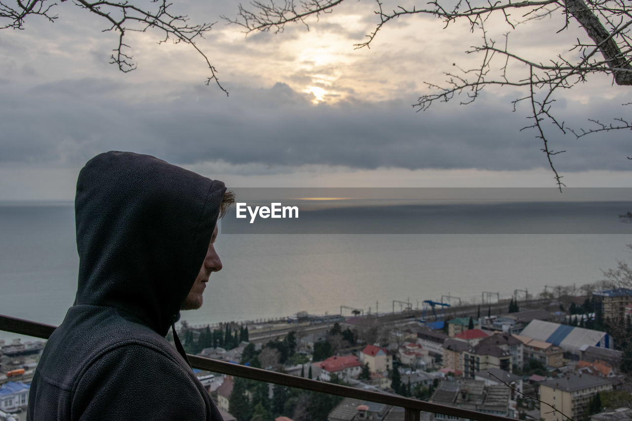 Man looking at city by sea against sky