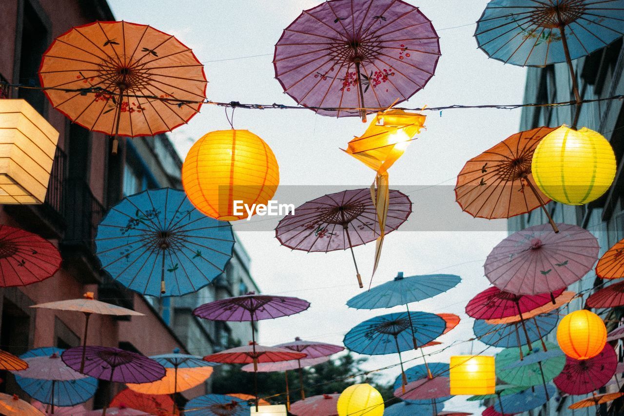 Low angle view of colorful umbrellas and lanterns against sky