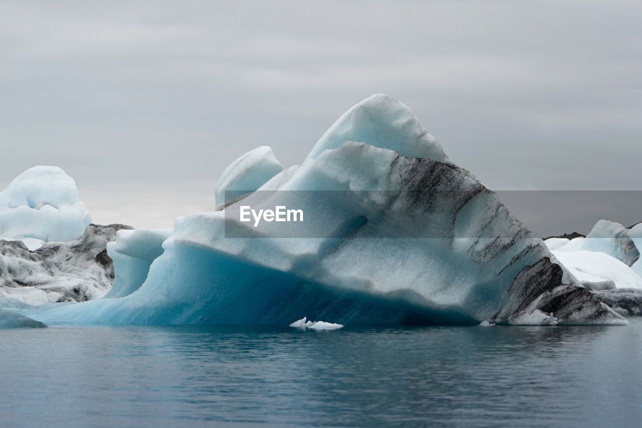 Close-up of icebergs on sea against sky