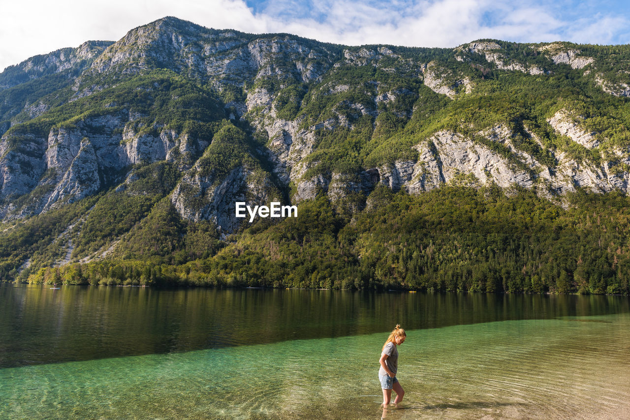 Woman walking in lake against mountains