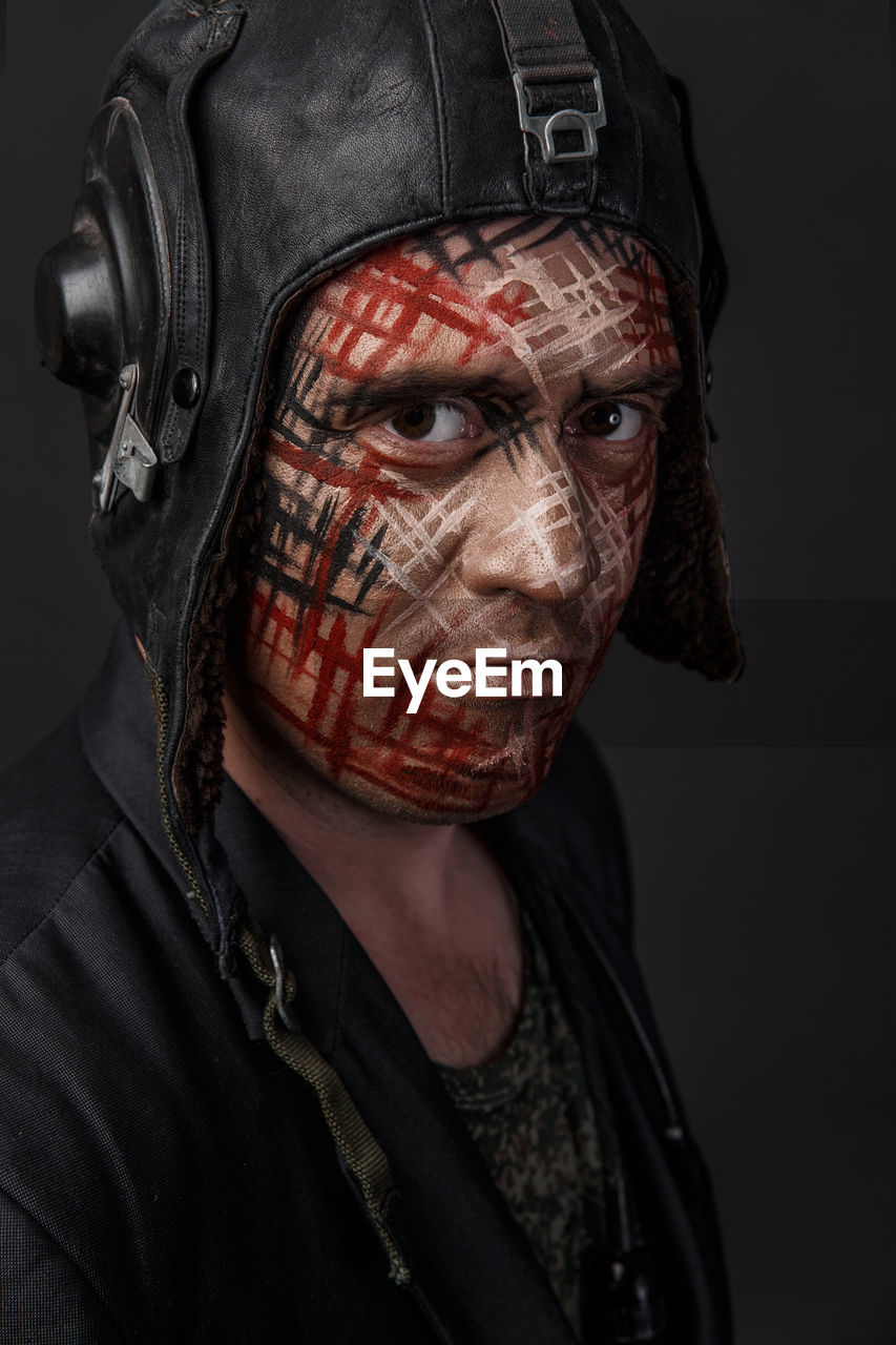 Close-up of man with face paint against black background