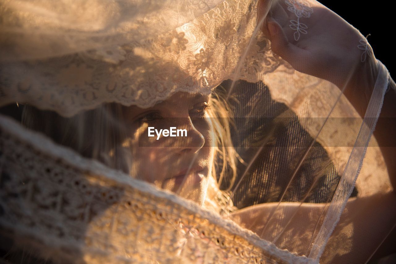 Close-up of bride wearing veil looking away while standing outdoors during sunset