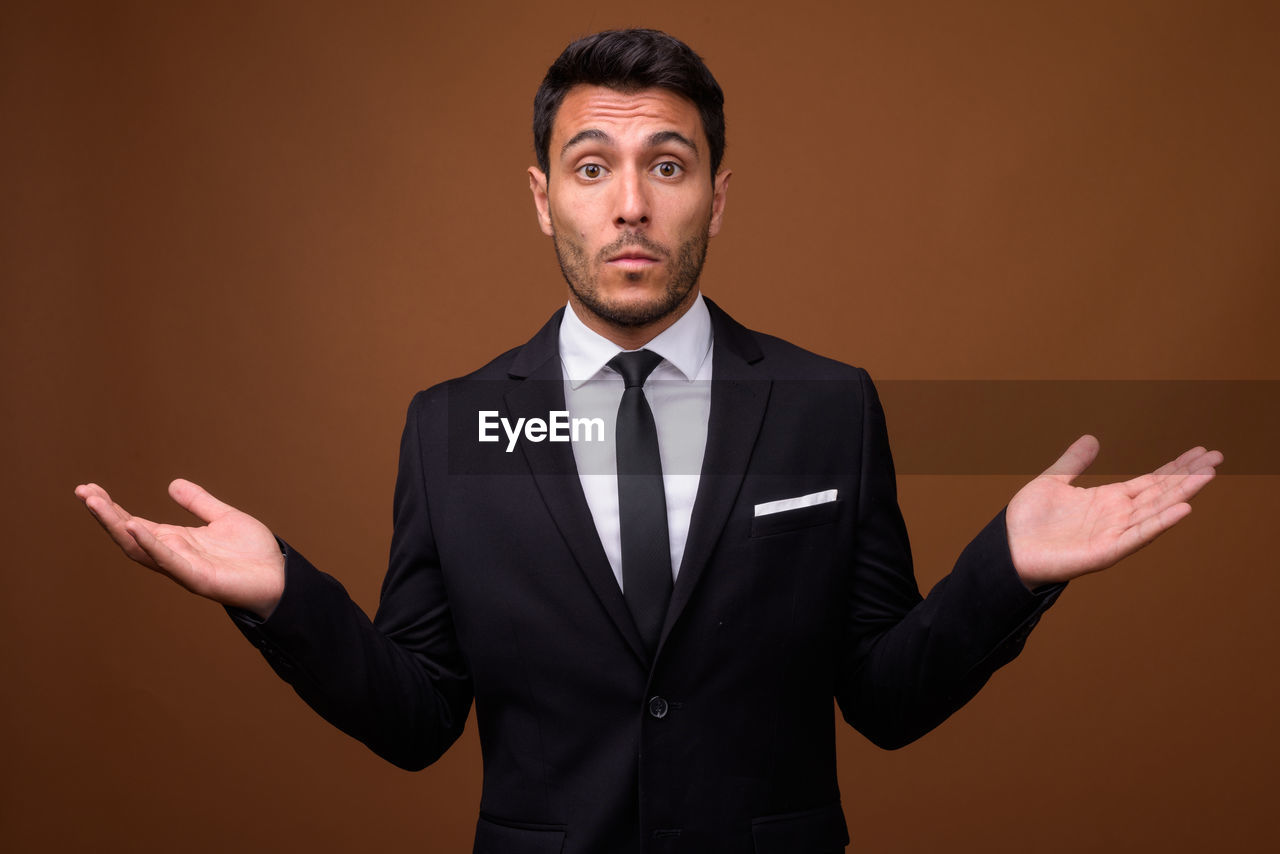 Portrait of young man standing against gray background